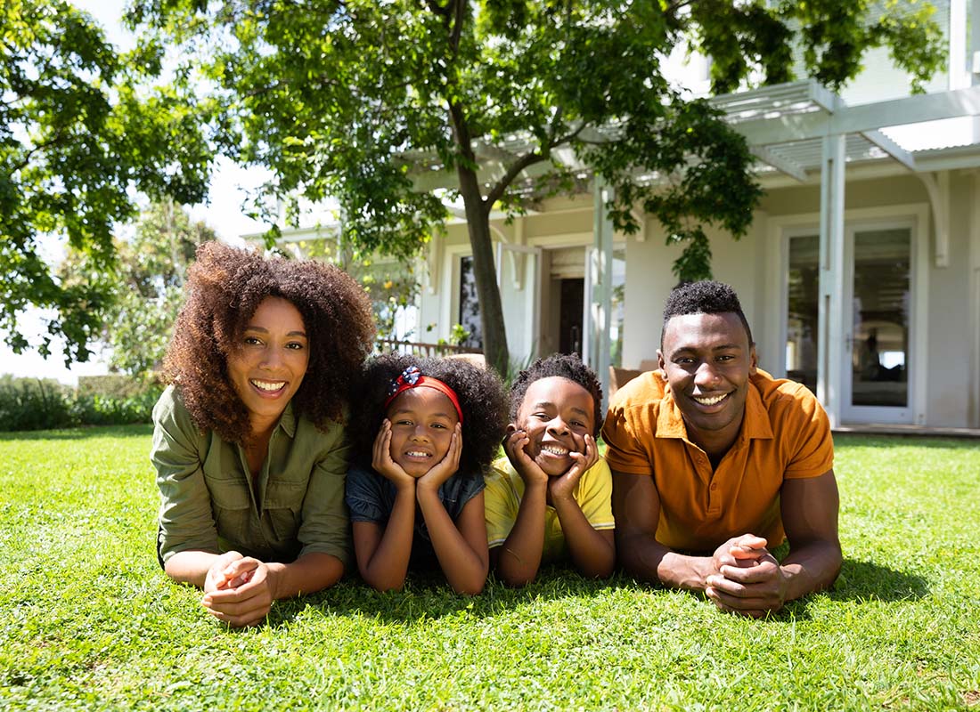 Personal Insurance - Closeup Portrait of a Family with Two Children Laying on the Green Grass in Their Backyard on a Sunny Day