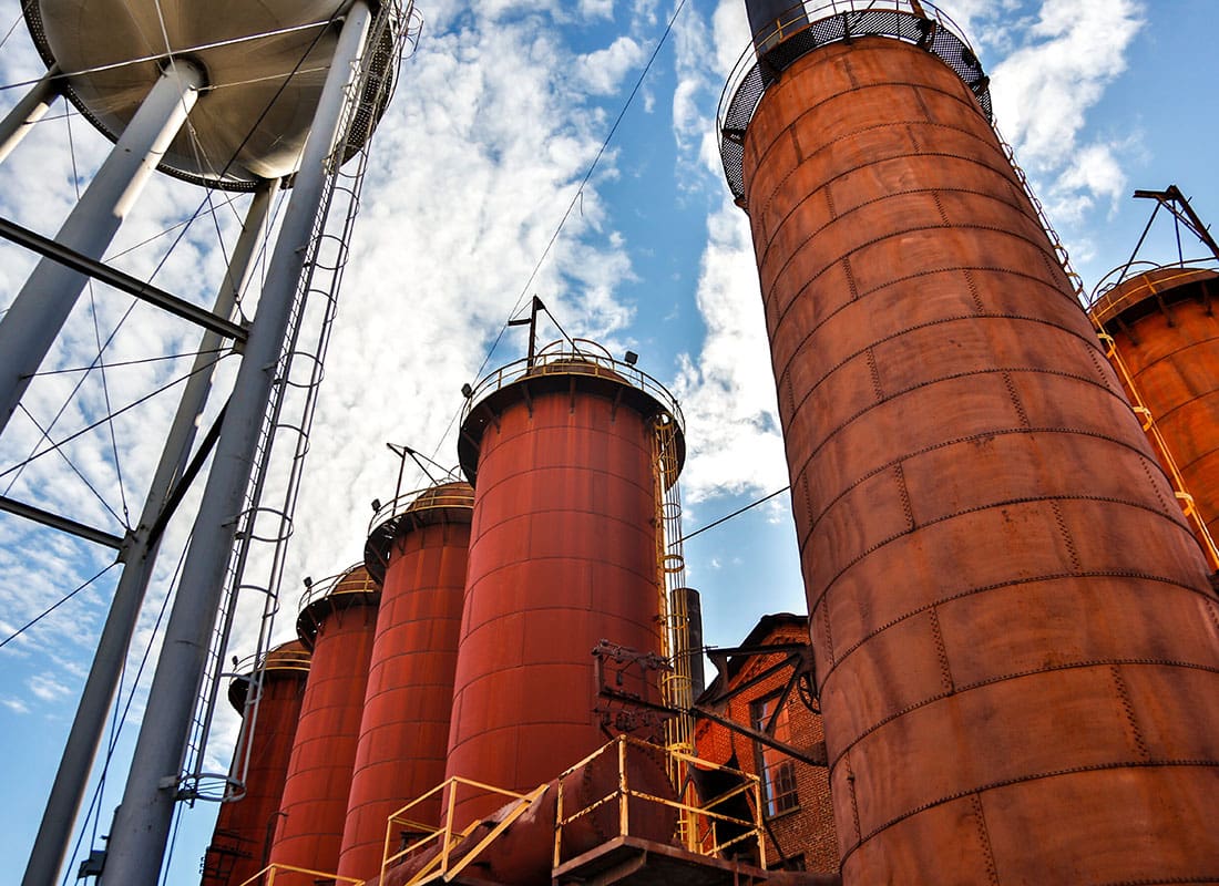 Read Our Reviews - View of Red Steel Mill Silos Against a Blue Sky Next to a Water Tower